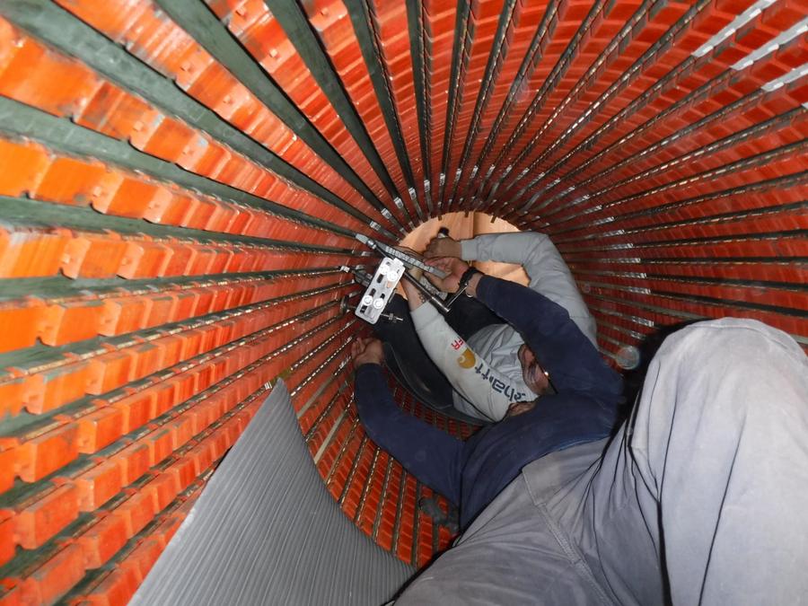 Looking along the inside of a stator core while a winder works on the slot wedges