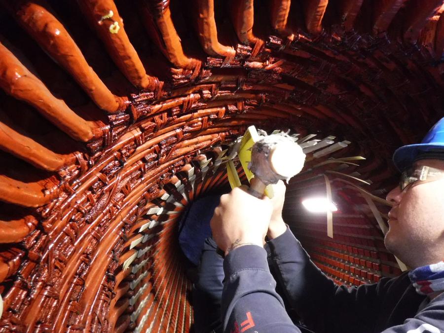 A winder in hard hat and safety glasses driving a slot wedge home with a mallet